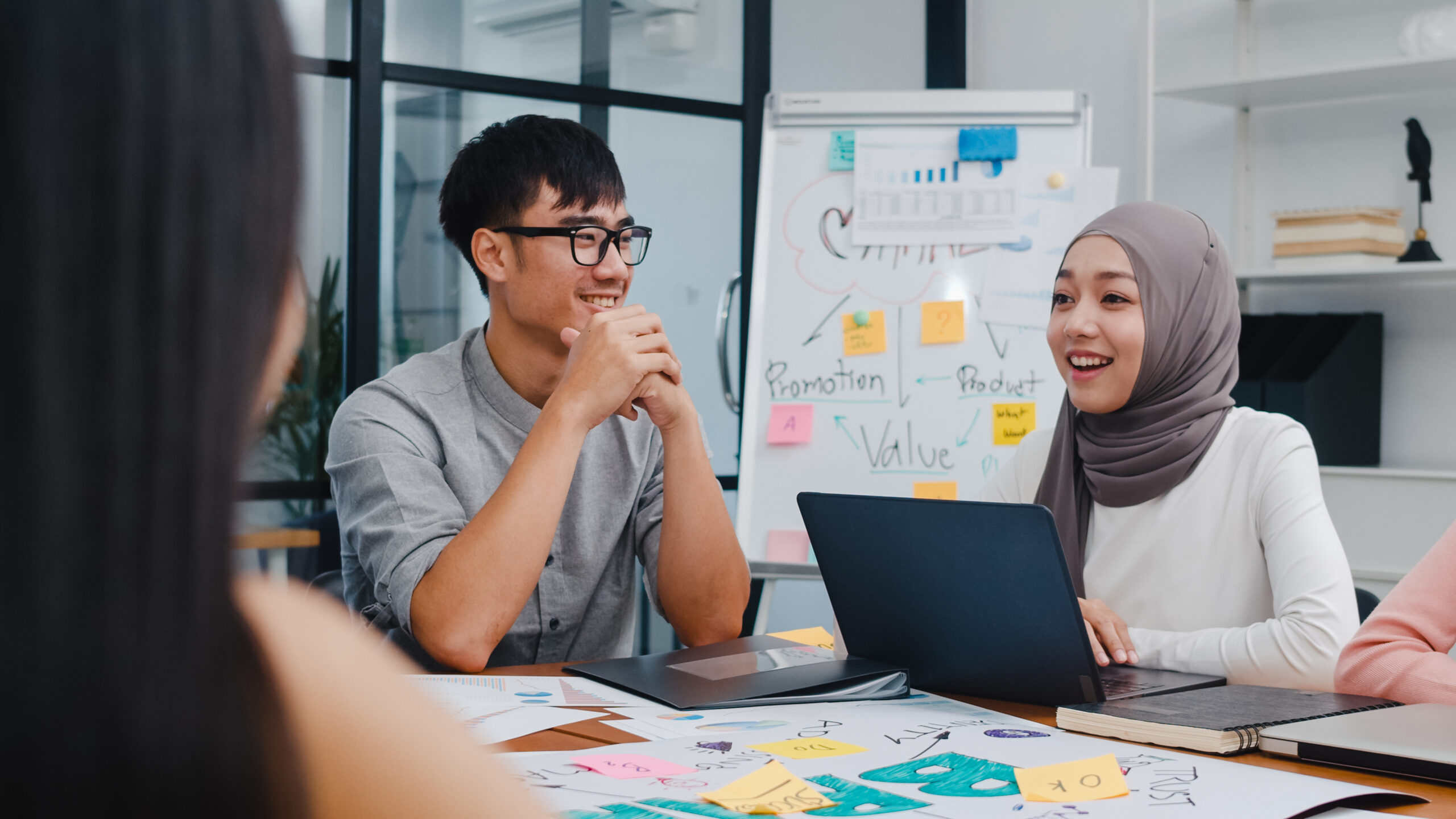 Multiracial team collaborating on mobile app design and business strategy in a modern office during a creative brainstorming session.
